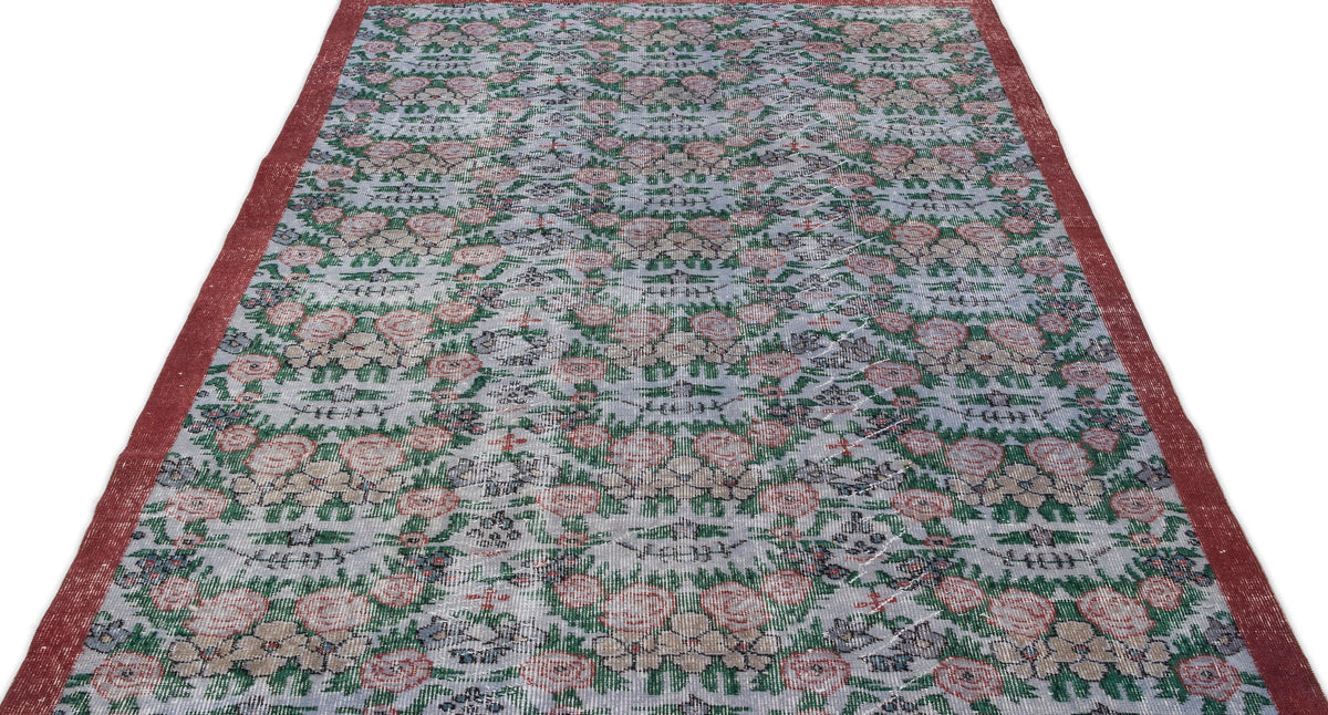 Distressed grey rug with a repeating floral pattern in red and green, featuring solid red side borders.