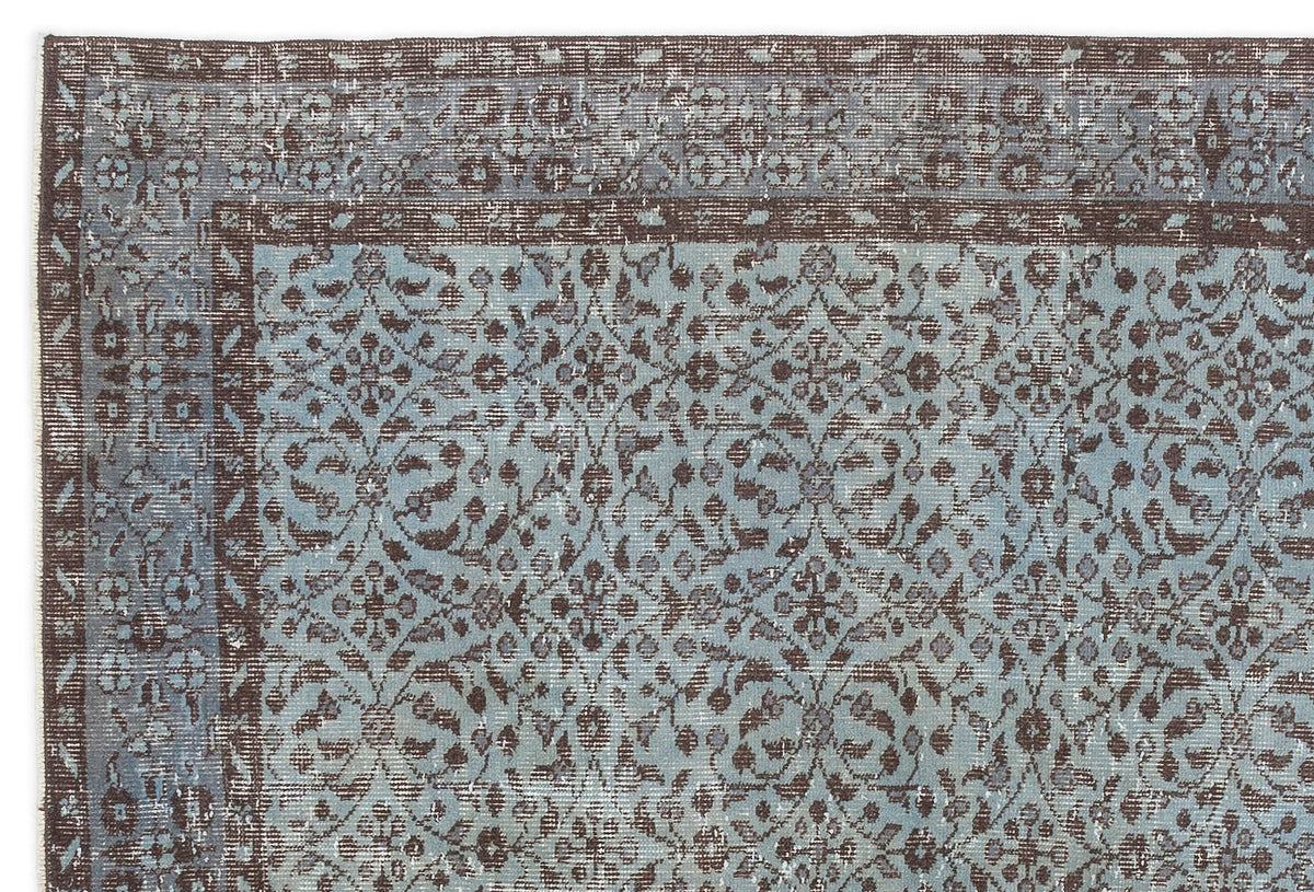 Distressed blue and brown rug with a traditional floral medallion pattern and a wide decorative border.