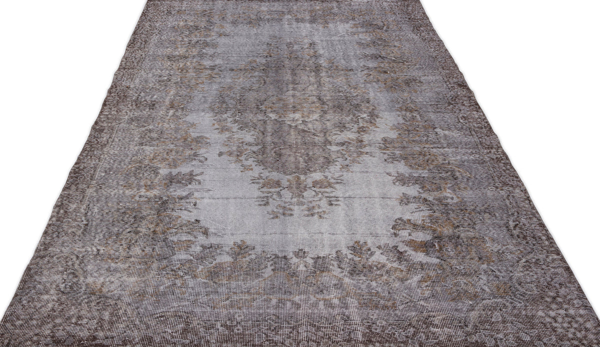 Grey and brown distressed vintage-style rug with a faded central floral medallion pattern on a white background.