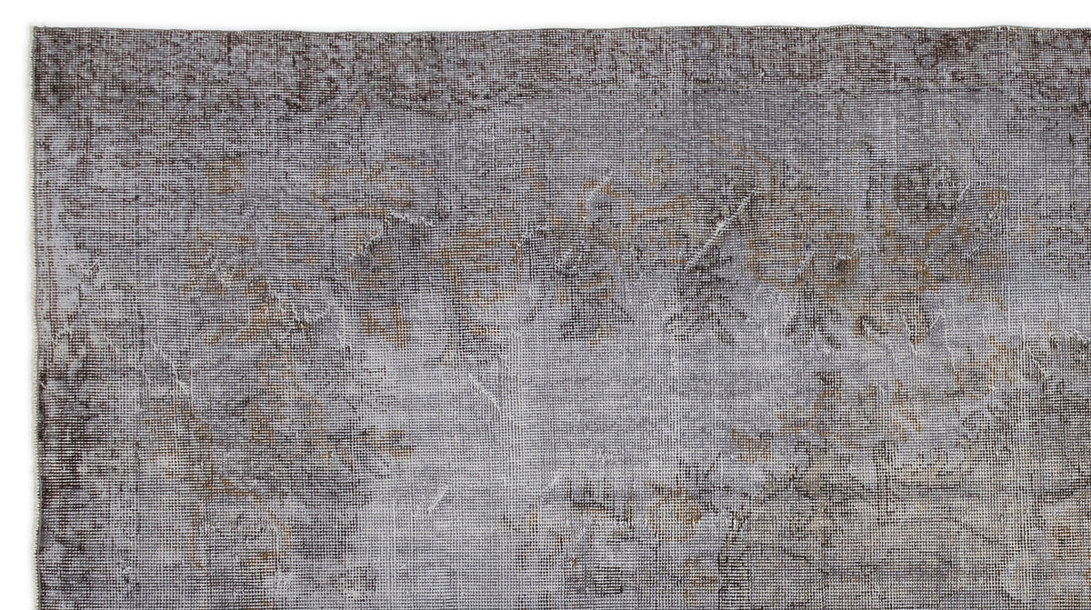 Grey and brown distressed vintage-style rug with a faded, low-pile floral pattern on a white background.