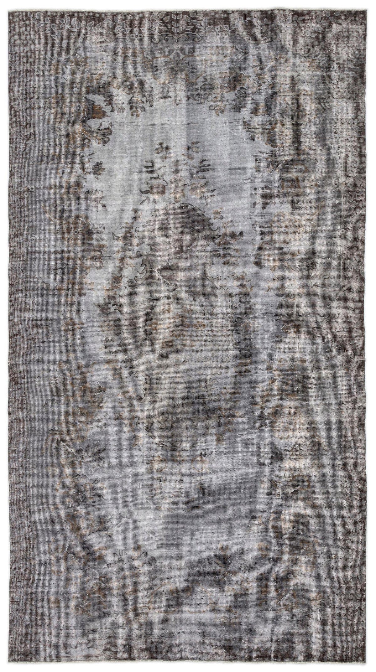 Grey and brown distressed vintage-style rug with a faded central floral medallion and ornate border.