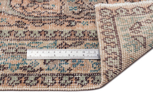 Load image 1 in gallery view. Beige, brown, and teal vintage-style rug with a floral medallion pattern, shown with a metal ruler for scale.