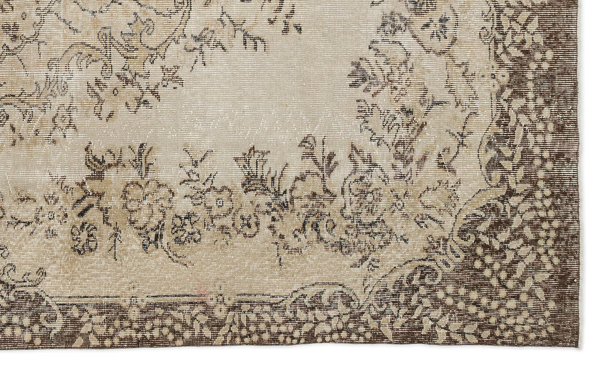 A close-up of the Petida - Vintage Medallion Rug (5'8 X 9'5) showcases its beige and brown tones, intricate floral and vine patterns, and slightly faded, distressed look for a timeless vintage appeal.