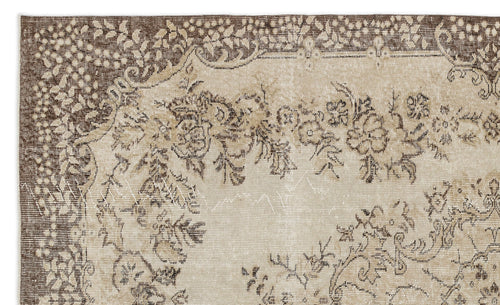 Load image 1 in gallery view. A section of the Petida - Vintage Medallion Rug (5'8 x 9'5) shows a beige background, brown floral motifs, and intricate borders. This vintage rug features a beautifully faded, distressed look.