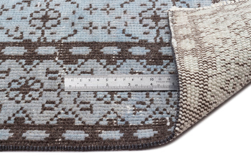 Load image 1 in gallery view. Light blue and dark brown rug with a geometric pattern, shown with a metal ruler for scale and a folded corner.