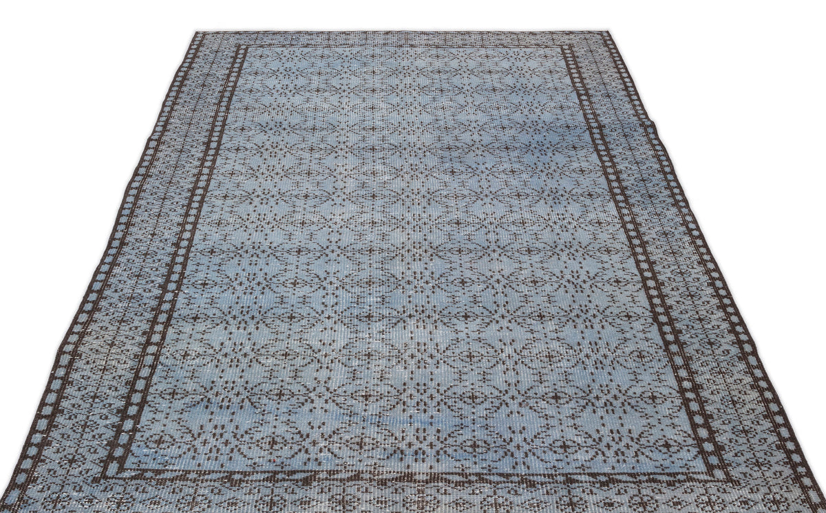 Light blue and dark brown distressed rug with a repeating geometric medallion pattern and a wide decorative border.