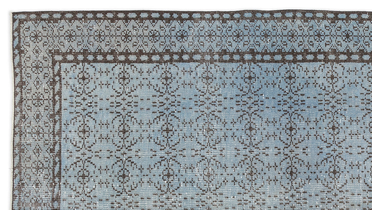 Light blue rug with a dark brown traditional floral medallion border and repeating geometric pattern.