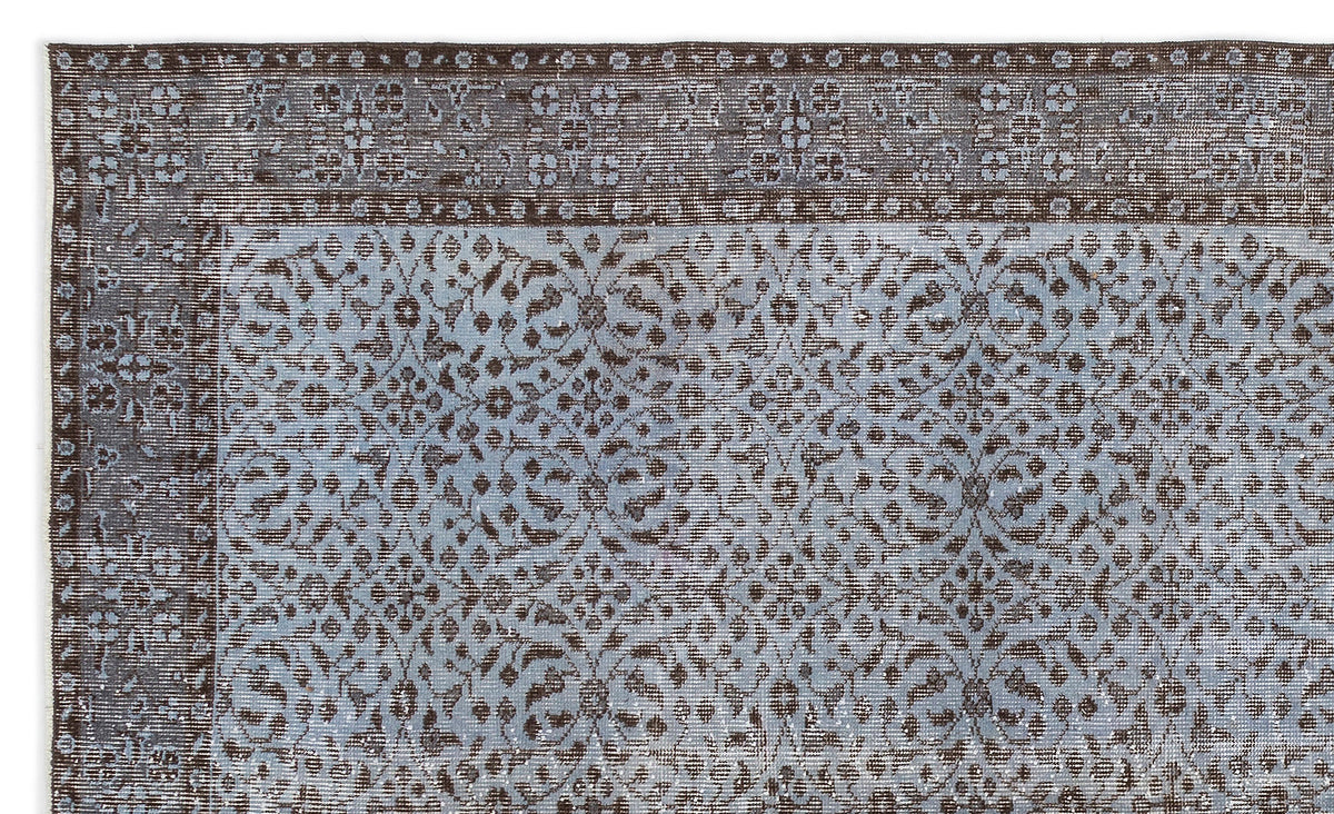 Distressed brown and light blue rug with a traditional floral medallion pattern and a wide decorative border.