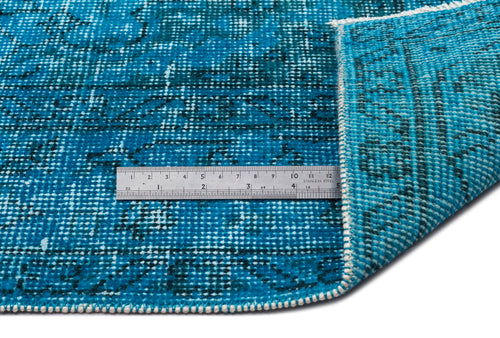 Load image 1 in gallery view. Bright blue distressed rug with a dark geometric pattern and a metal ruler showing pile texture on a white background.