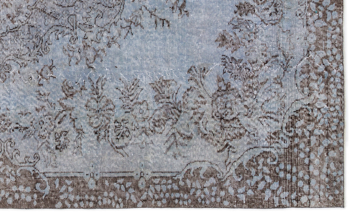 Light blue and dark brown distressed rug with a traditional floral medallion pattern and a detailed border.
