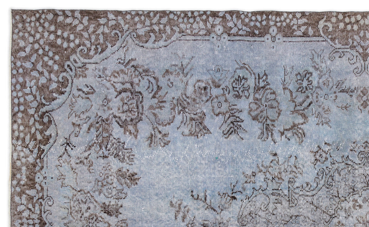 Distressed light blue and brown rug with a traditional floral medallion pattern and ornate border.