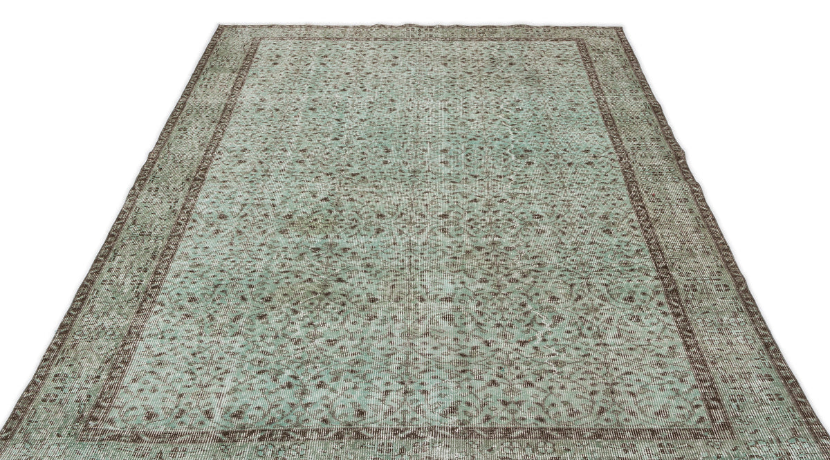 Distressed mint green and brown rug with a traditional floral medallion pattern and a wide decorative border.