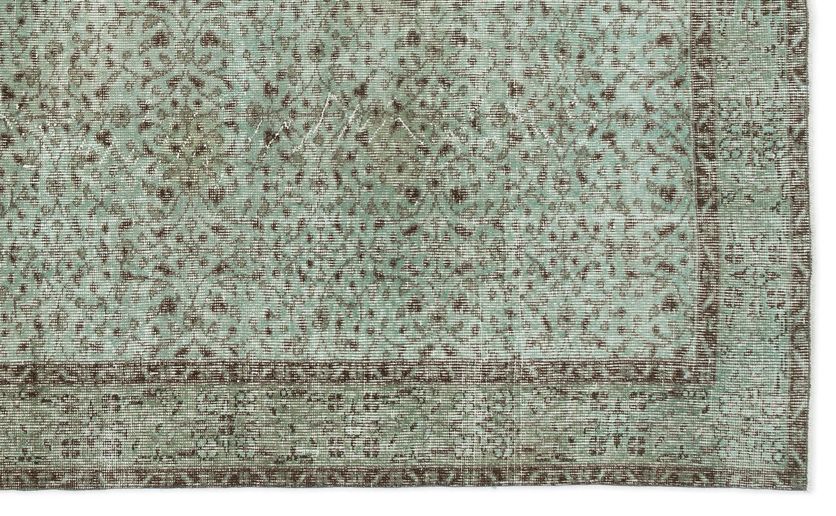 Distressed mint green and brown rug with a traditional floral medallion pattern and a wide decorative border.