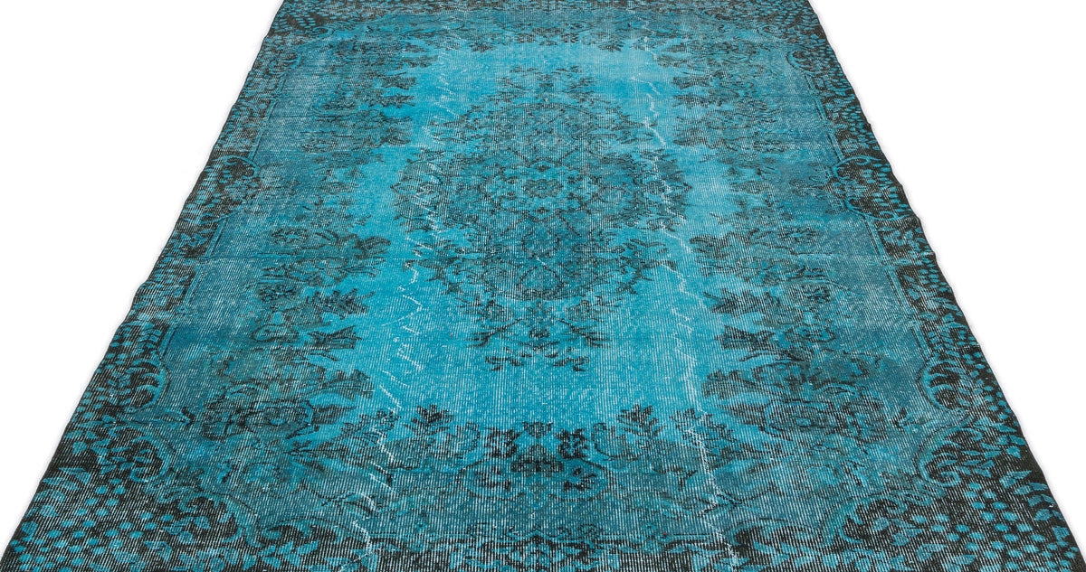 Distressed turquoise and black rug with a traditional floral medallion pattern on a white background.
