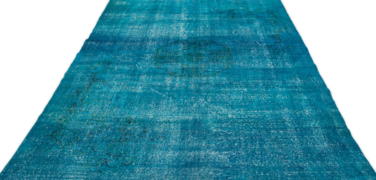 Distressed turquoise rug with a faded central medallion and subtle dark line patterns on a white background.
