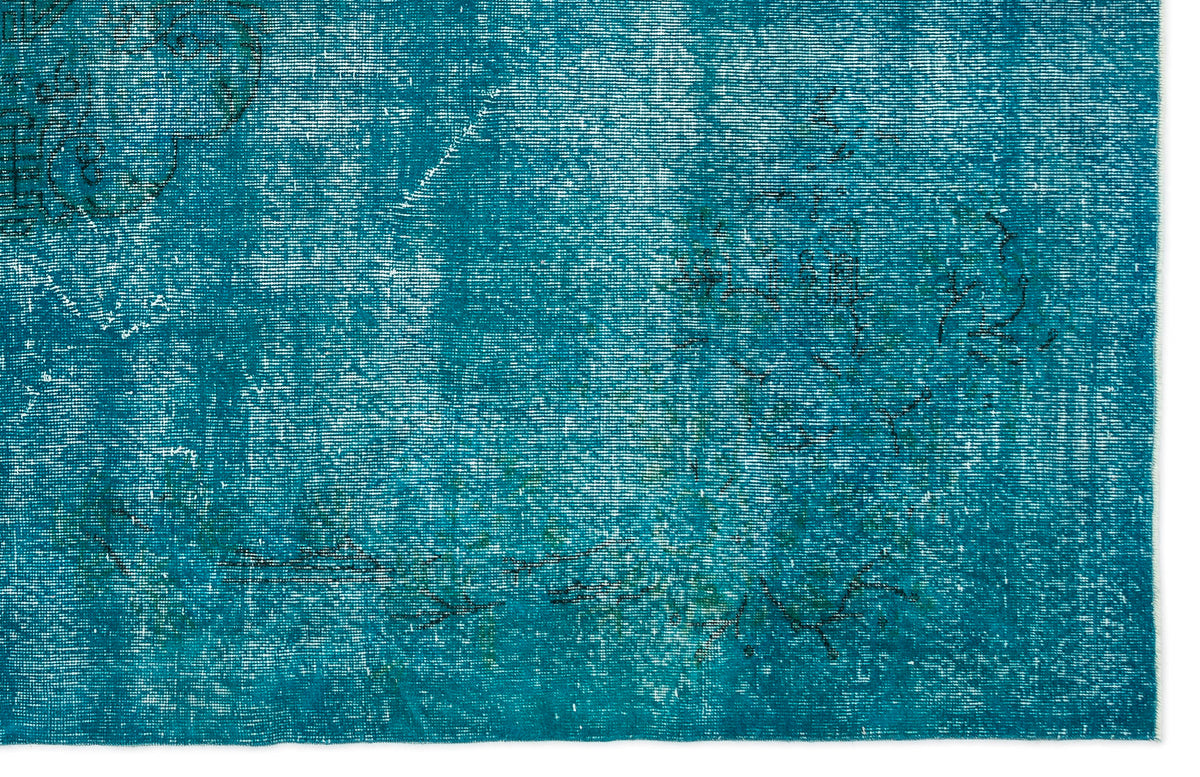 Teal distressed rug with a faded, overdyed traditional floral pattern and white worn accents.