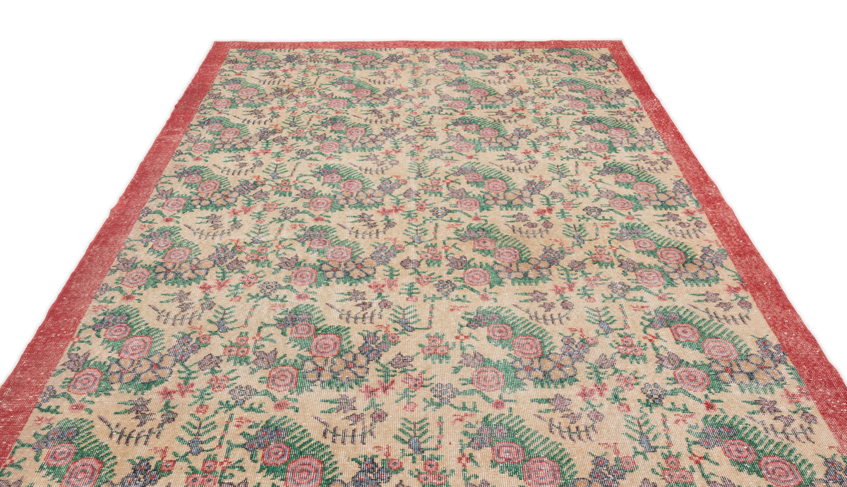 Beige vintage-style rug with a red border and a repeating floral pattern in green, pink, and blue.