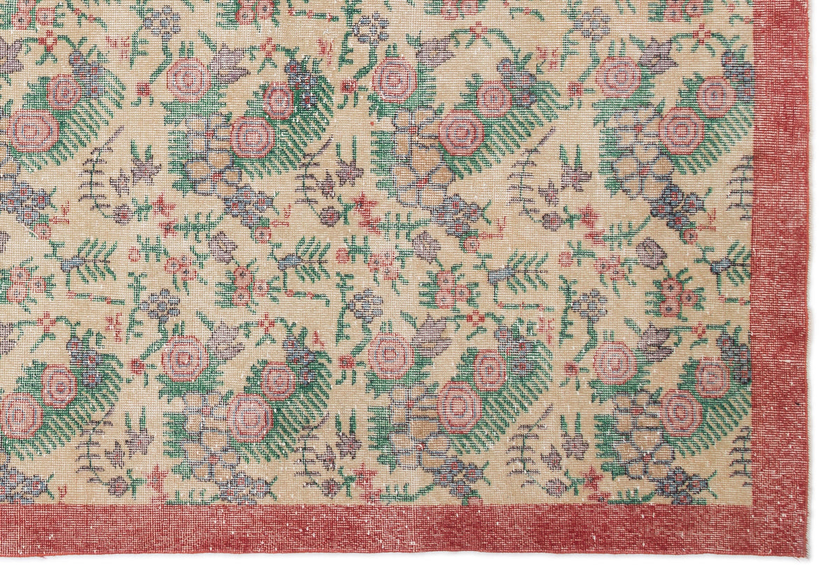 Beige rug with a floral pattern in pink, green, and blue, featuring a solid red border.