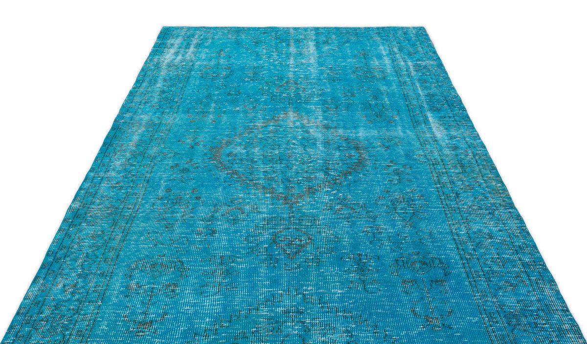 Bright turquoise distressed rug with a faded dark grey traditional medallion pattern on a white background.