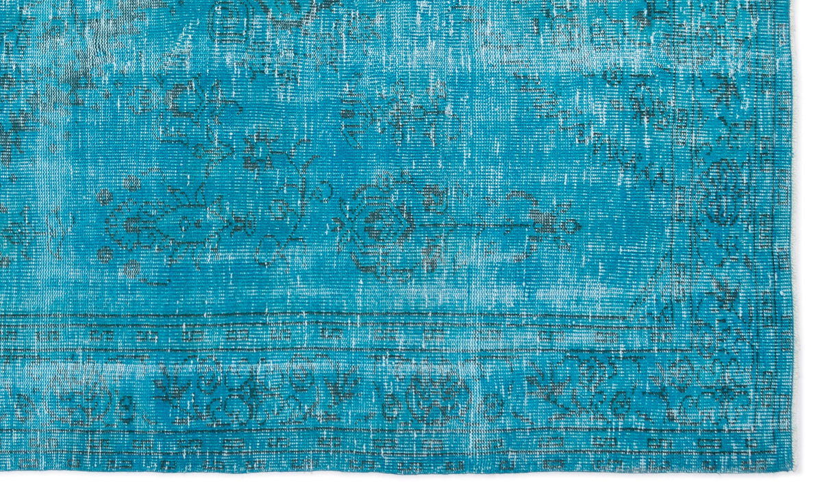 Bright turquoise rug with a distressed, faded floral medallion pattern and dark grey border details.