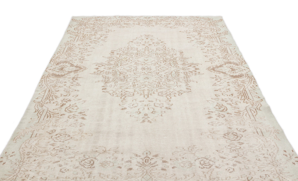 Cream and beige area rug with a faded traditional floral medallion pattern on a white background.