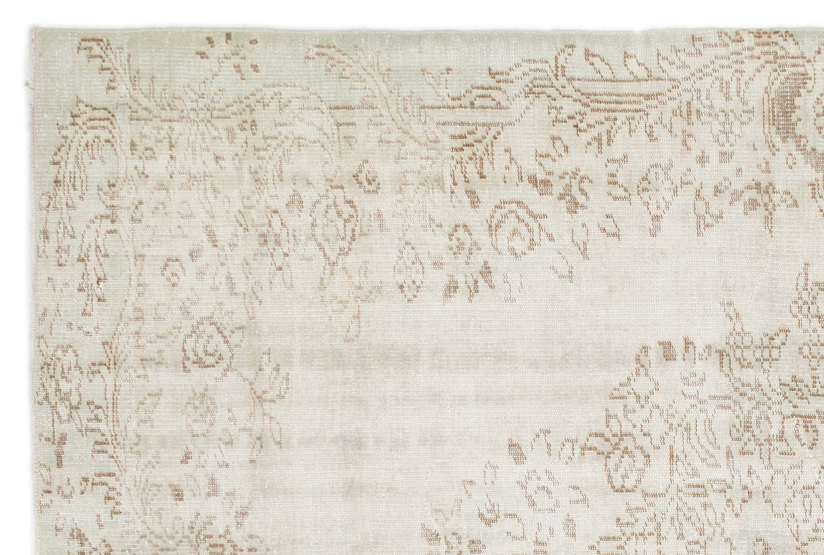 Cream rug with a faded, light brown floral medallion pattern on a white background.