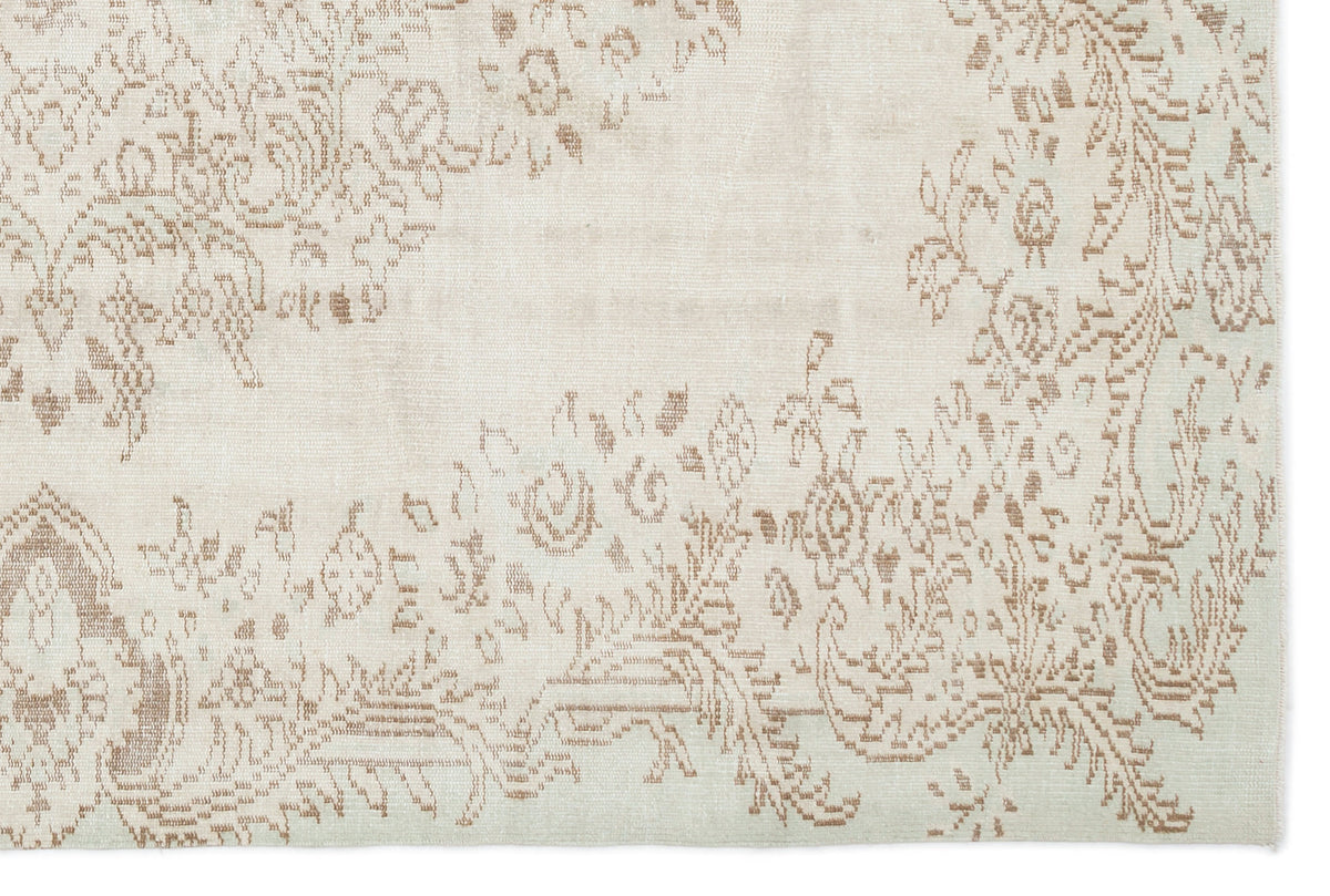 Off-white rug with a faded, light brown floral medallion pattern and distressed texture.