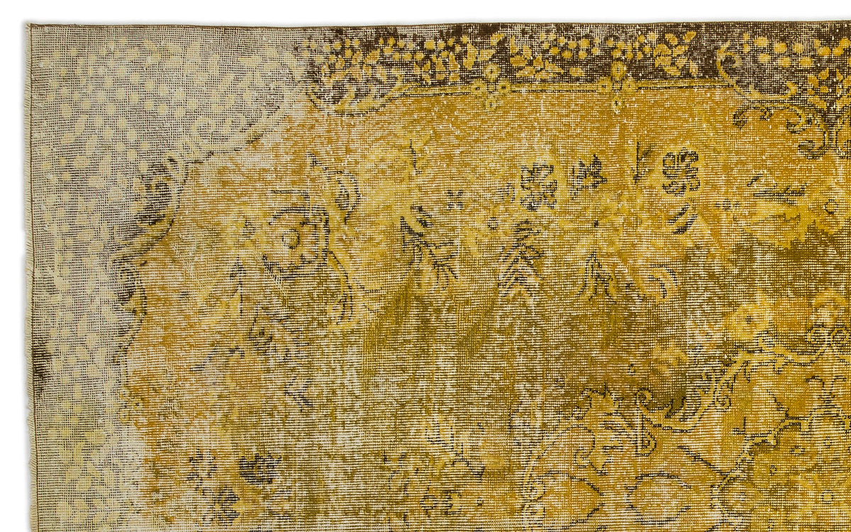 Distressed mustard yellow and brown vintage-style rug with a faded floral medallion pattern.