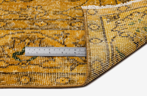 Load image 1 in gallery view. Mustard yellow and brown distressed traditional rug with a folded corner and a metal ruler for scale.