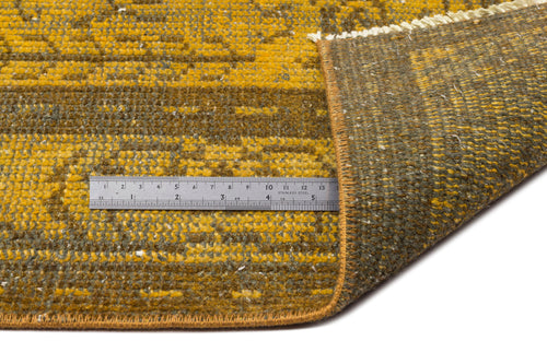 Load image 1 in gallery view. Mustard yellow and olive green distressed patterned rug with a folded corner and a metal ruler for scale.