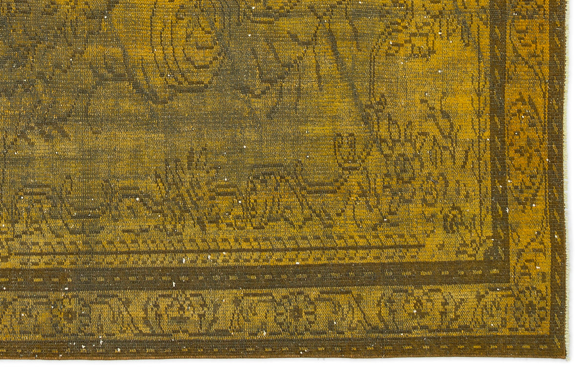 Mustard yellow and dark brown vintage-style rug with a distressed floral medallion pattern and a decorative border.