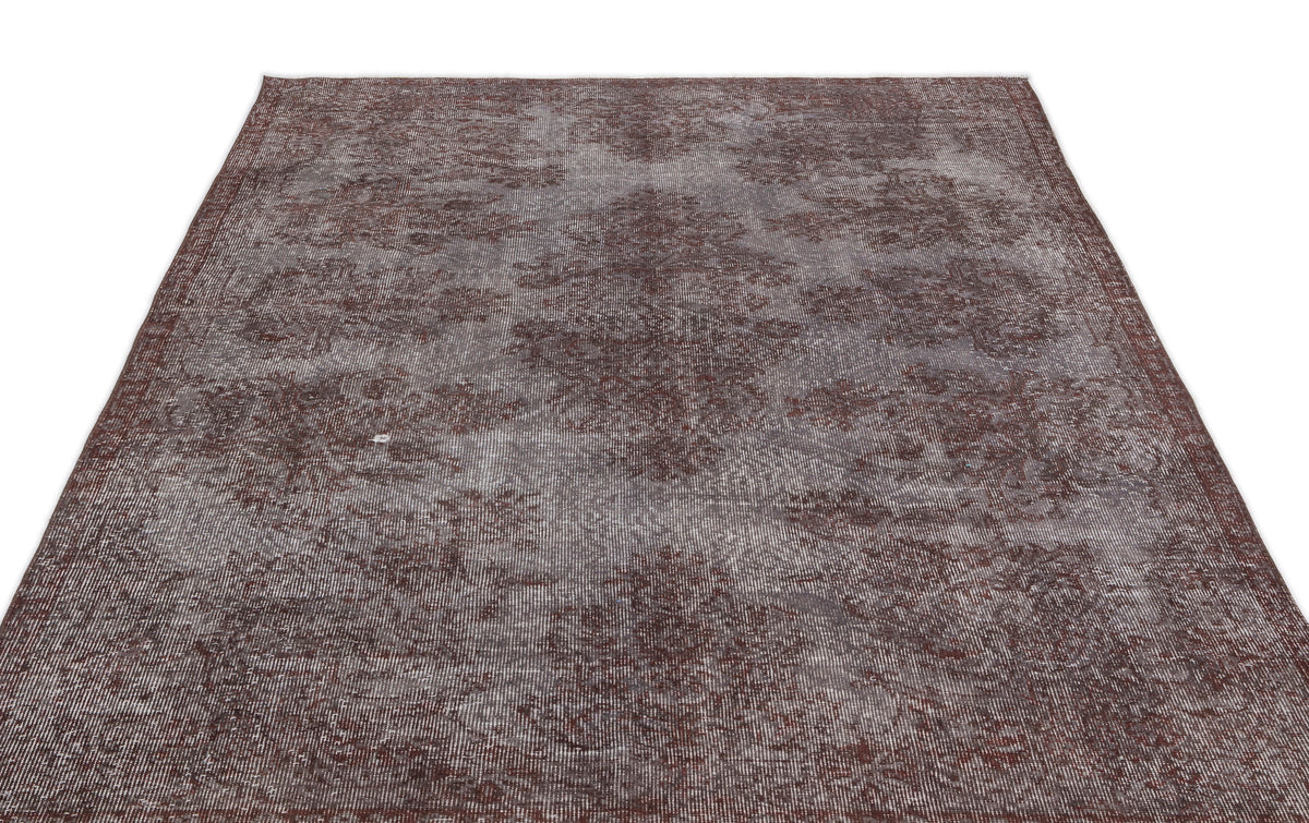 Dark brown and grey distressed vintage-style rug with a faded floral medallion pattern.