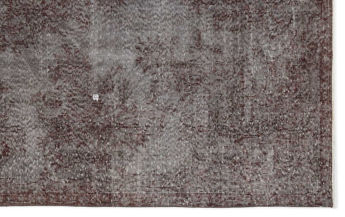 Dark brown and grey distressed rug with a faded, textured vintage pattern.