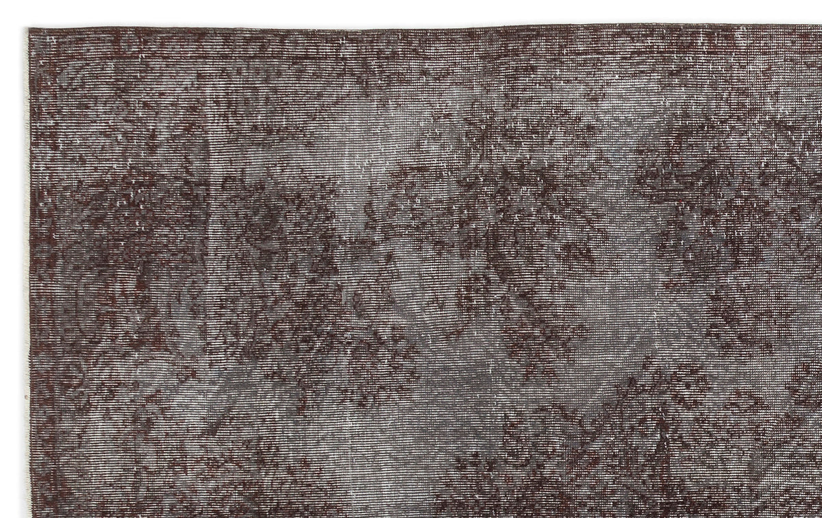 Dark brown and grey distressed vintage-style rug with a faded, abstract floral pattern.