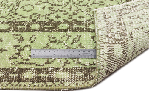 Load image 1 in gallery view. Light green and dark brown distressed traditional rug with a folded corner and a metal ruler for scale.