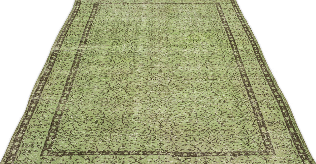 Sage green distressed rug with a dark brown traditional border and intricate faded floral pattern.