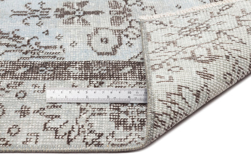 Load image 1 in gallery view. Light blue and brown distressed traditional pattern rug with a folded corner and a metal ruler for scale.
