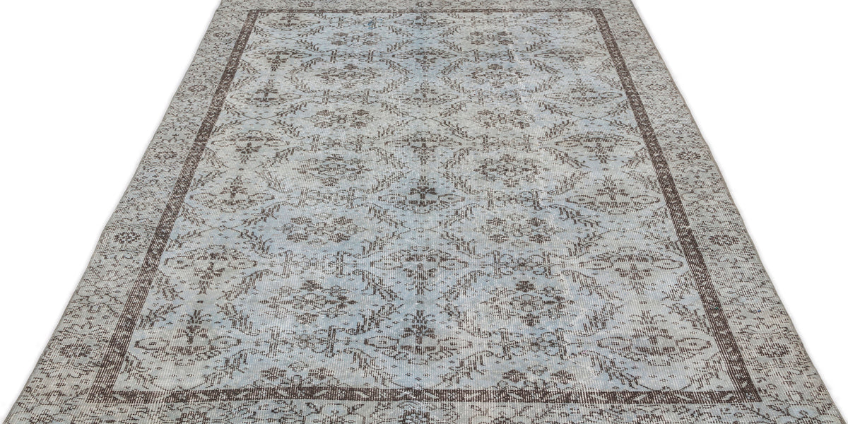 Light blue and brown distressed rug with a traditional floral medallion pattern and a dark border on a white background.