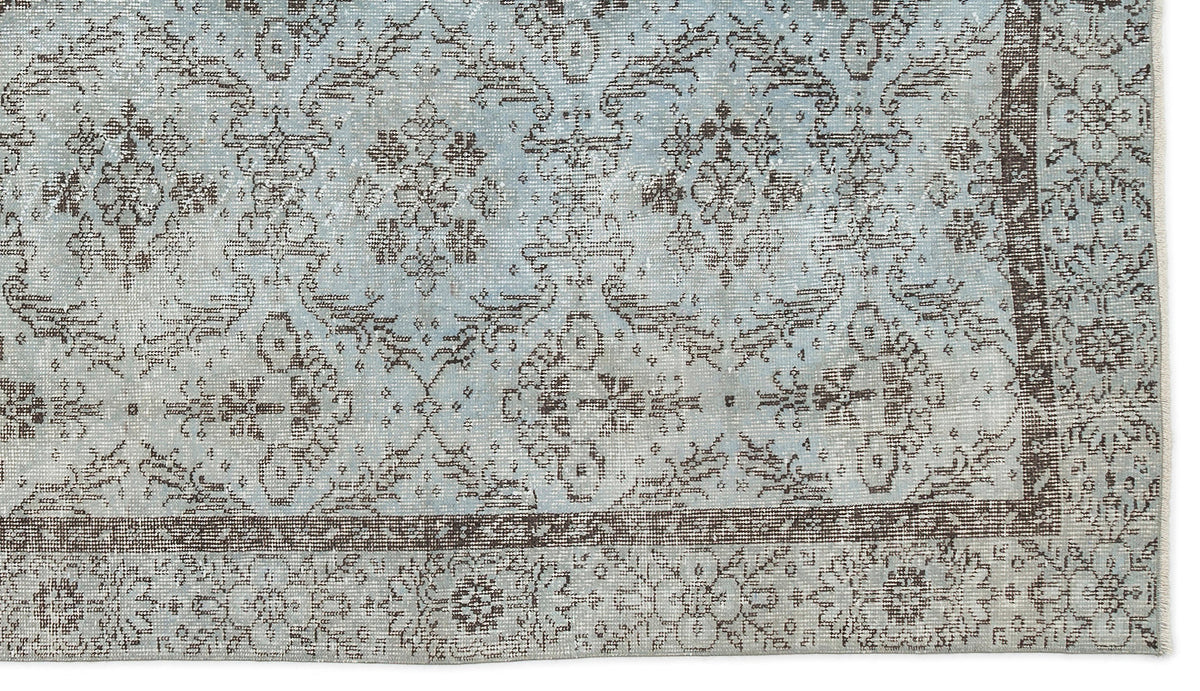 Light blue and brown distressed rug with a traditional floral medallion pattern and a decorative border.