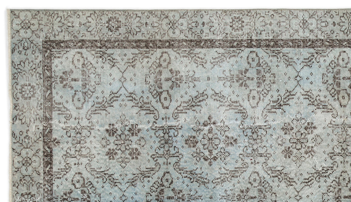 Light blue and brown traditional rug with a distressed floral medallion pattern and a detailed border.