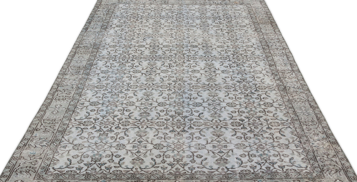 Grey and beige vintage-style rug with a repeating floral vine pattern and a decorative border on a white background.