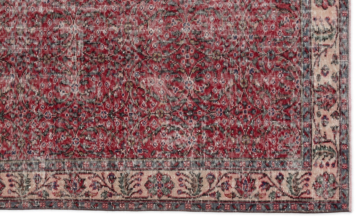 Distressed red and cream traditional rug with a dense floral medallion pattern and a wide decorative border.
