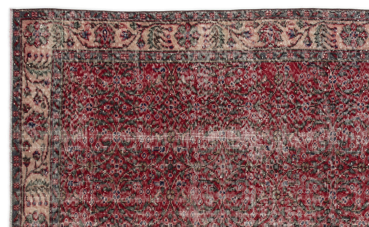 Distressed red and charcoal traditional rug with a floral medallion pattern and a decorative border.
