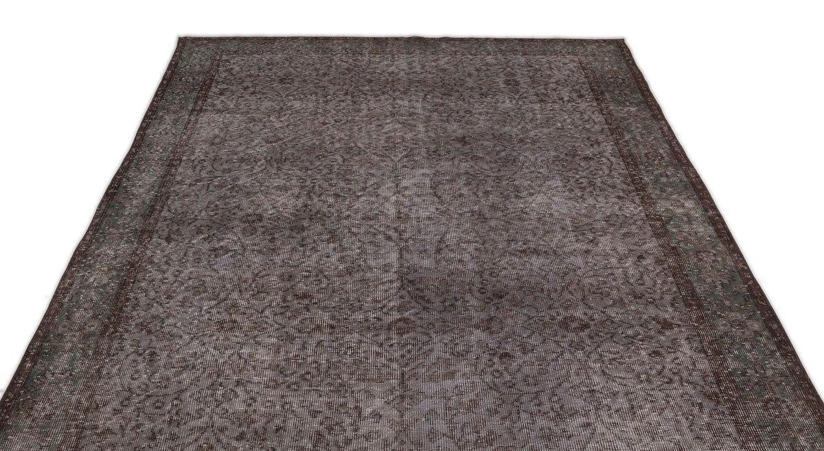 Dark brown and grey distressed rug with a traditional floral medallion pattern and a wide border.