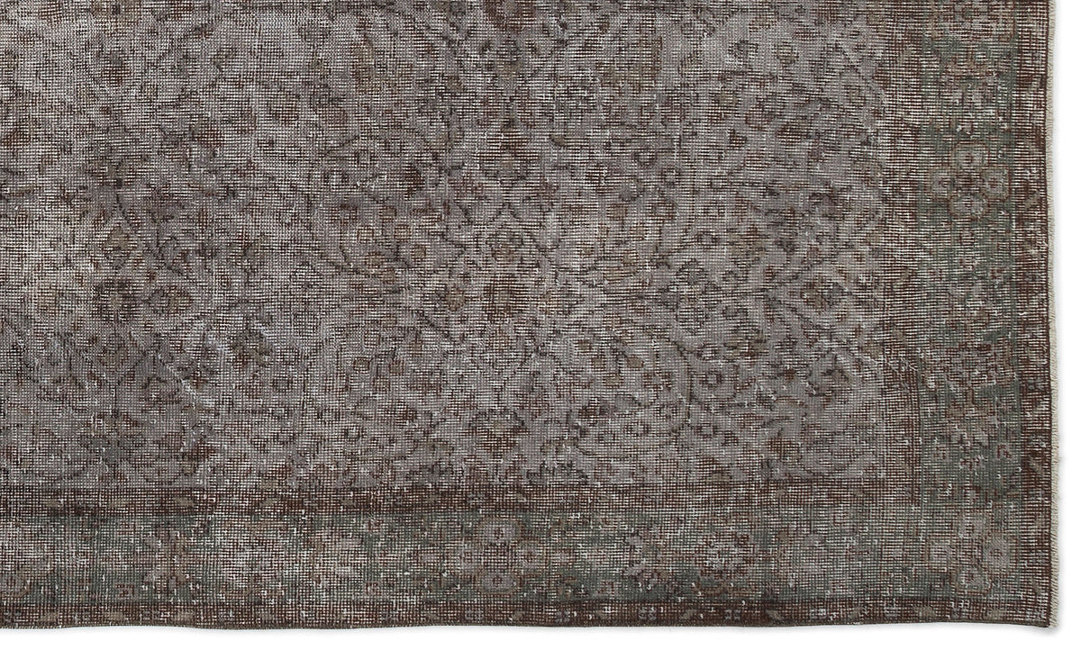 Distressed brown and grey rug with a faded traditional floral medallion pattern and a bordered edge.