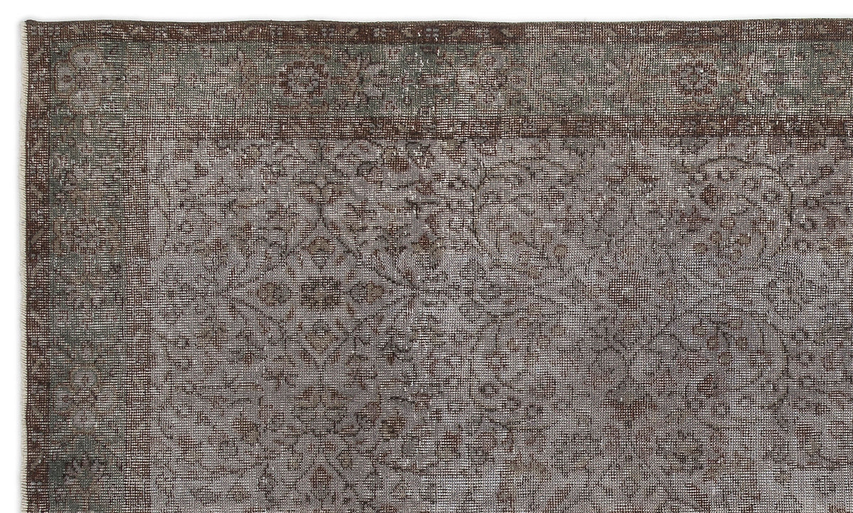 Distressed brown and sage green rug with a traditional floral medallion pattern and a wide border.