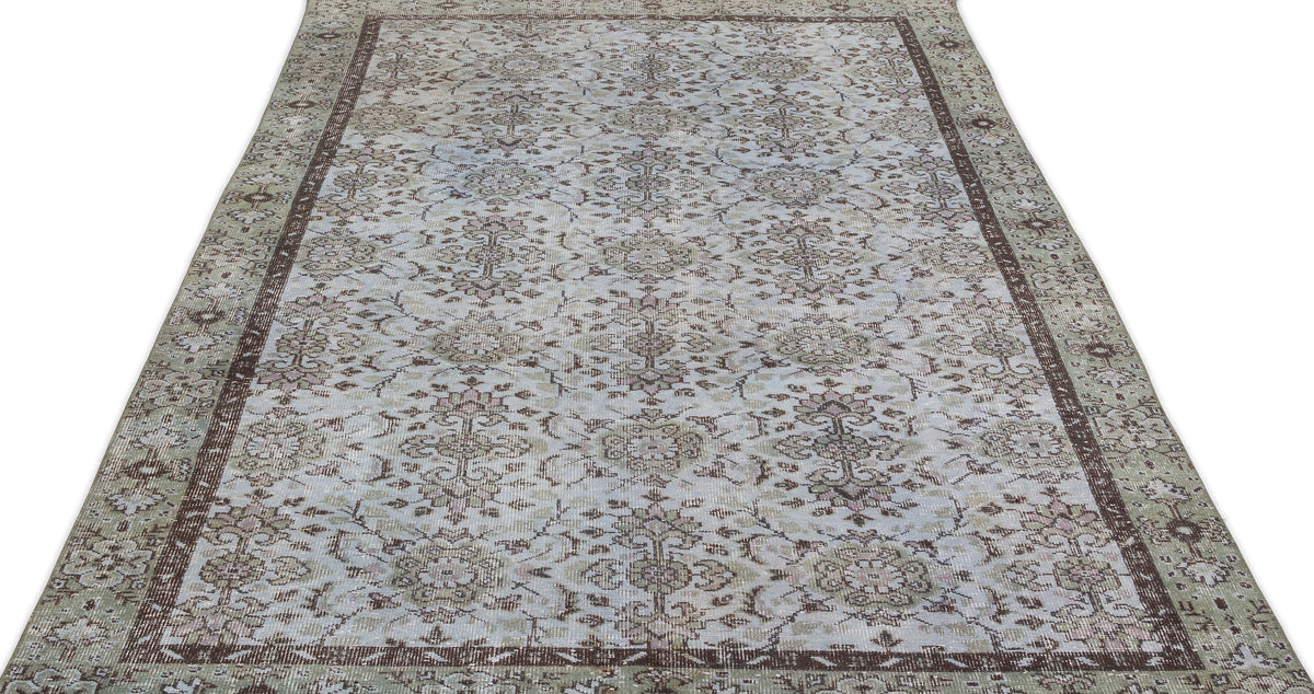 Light blue and brown vintage-style rug with a distressed floral medallion pattern and a wide decorative border.