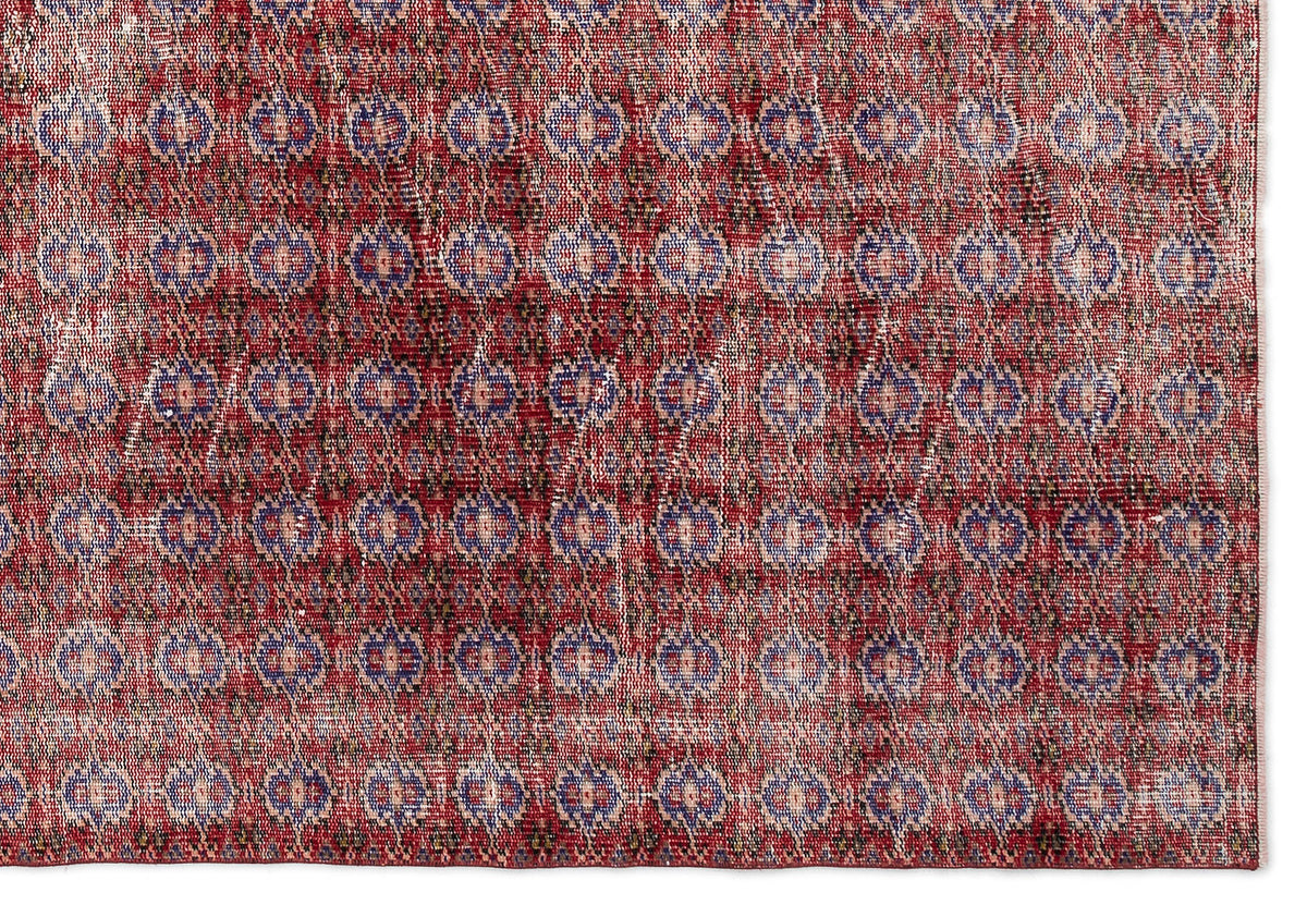 Red and blue distressed rug with a repeating geometric diamond and medallion pattern on a white background.