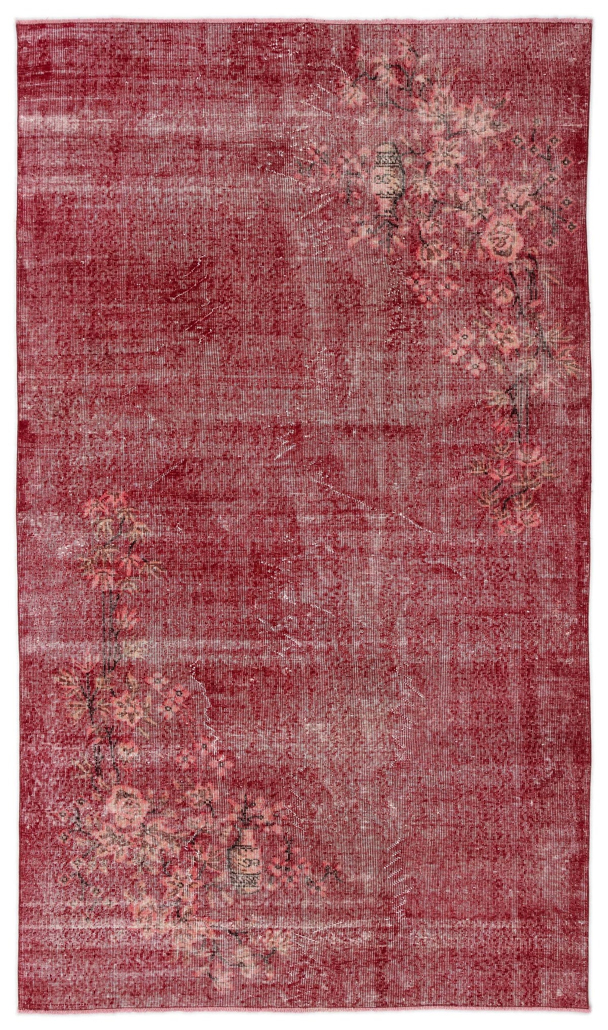 Distressed deep red rug with an asymmetrical floral branch pattern in muted pink and beige tones.