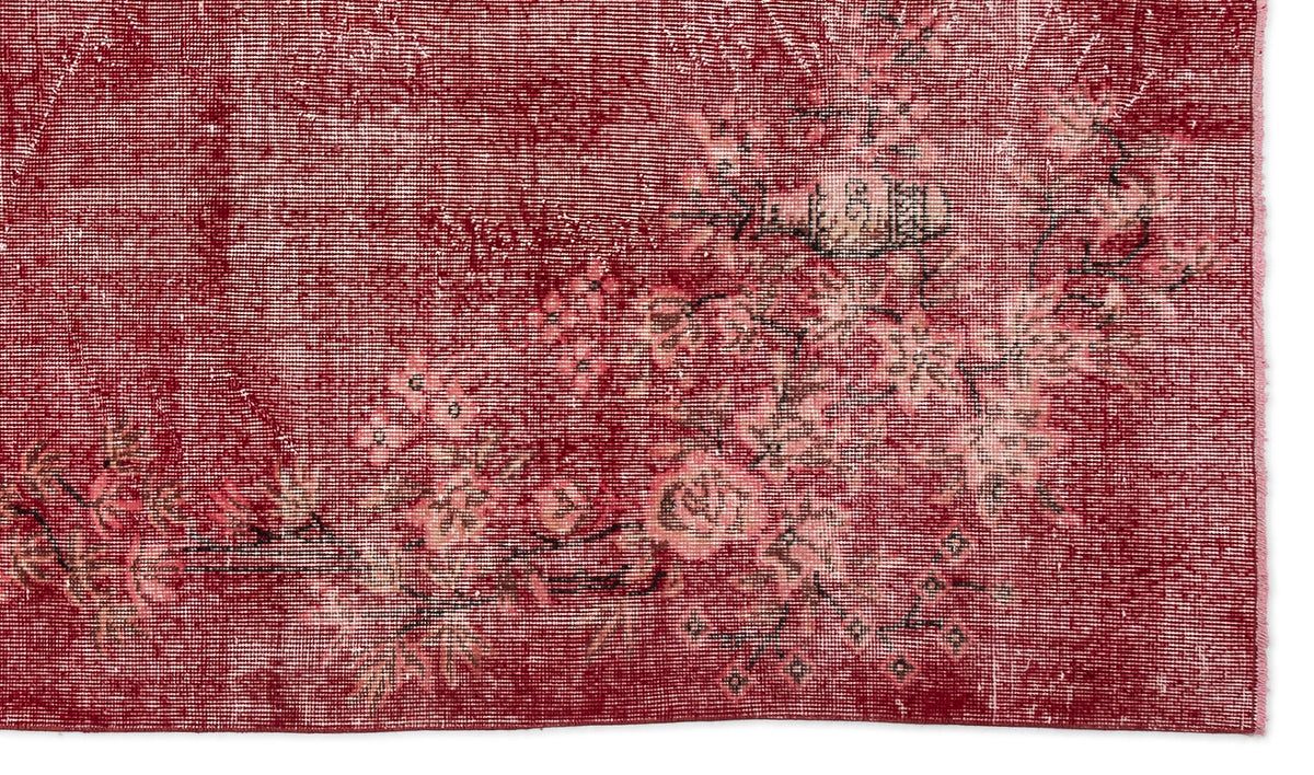 Deep red distressed rug with a faded floral pattern in pink and black on a white background.